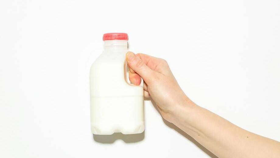 A hand holding a carton of milk